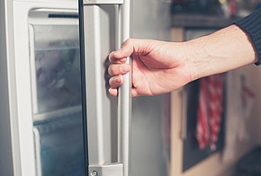 Hand an der geöffneten Kühlschranktür