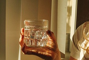 Glas Wasser in einer Hand.